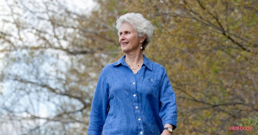 Smiling older woman out for a walk among the trees