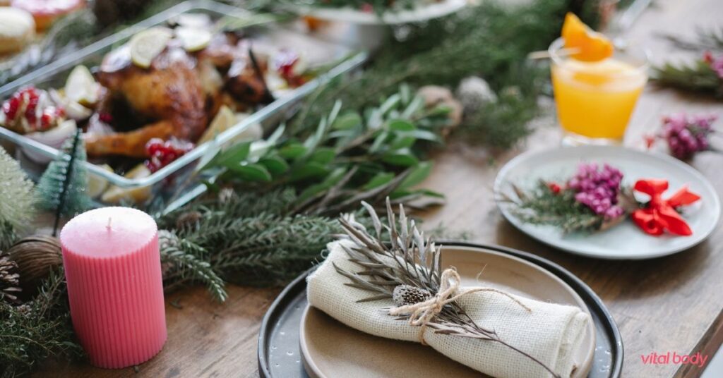 A festive holiday table with a roast, evergreen branches, a pink candle and linen napkins, for enjoying the season on Ideal Protein