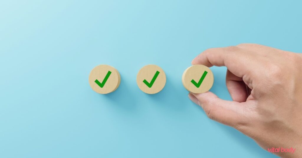 A hand placing the third of three wooden checkmark tokens, a checklist for getting organized on Ideal Protein