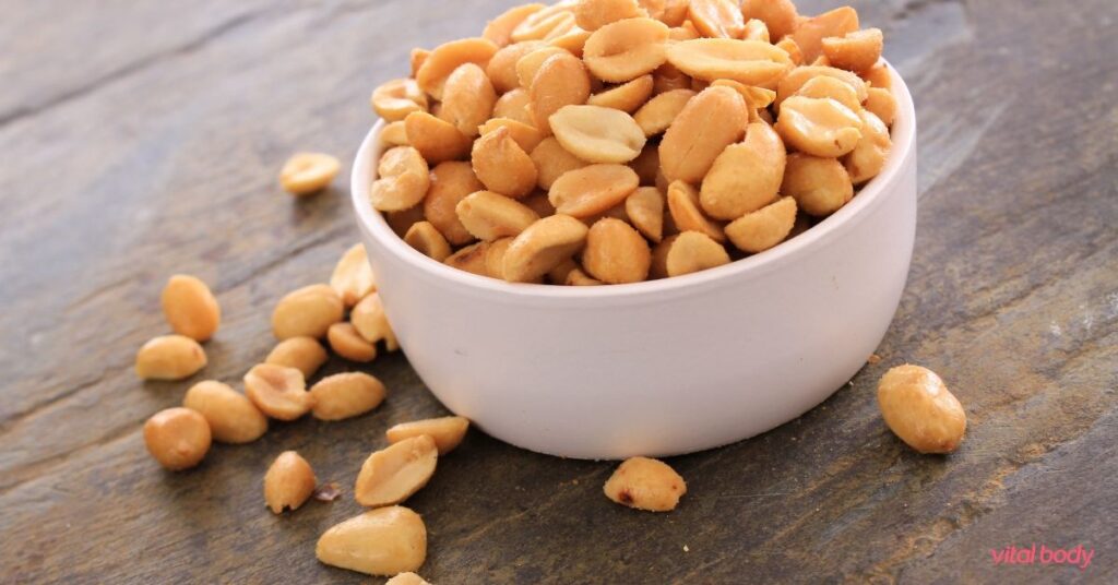 A white bowl of roasted peanuts on a slate table, a simple snack idea for Ideal Protein Phase 2 and 3