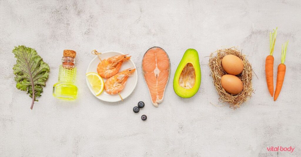 Kale, olive oil, shrimp, salmon, avocado, eggs and carrots in a row, comparing Ideal Protein and keto foods