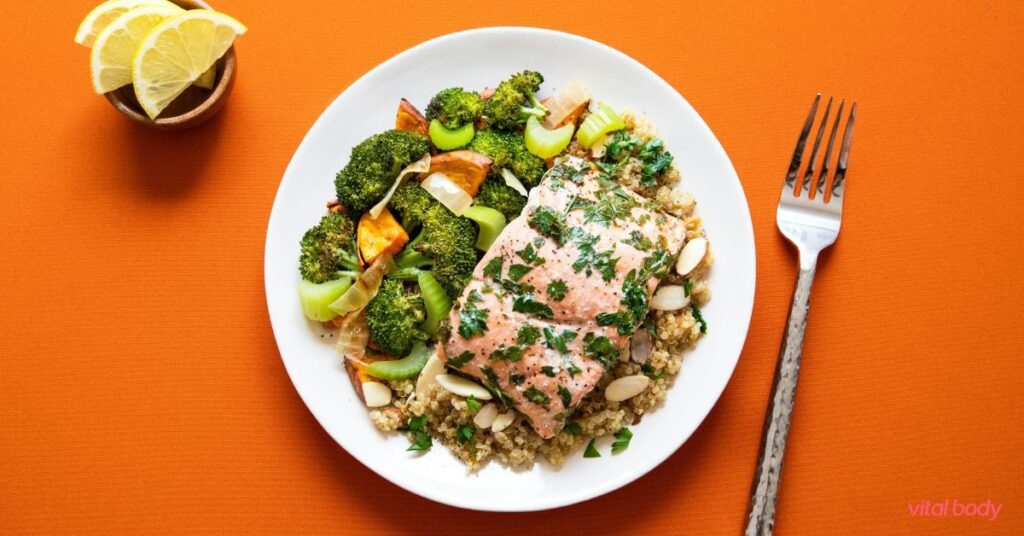 Salmon on quinoa with roasted broccoli and sweet potato on a white plate