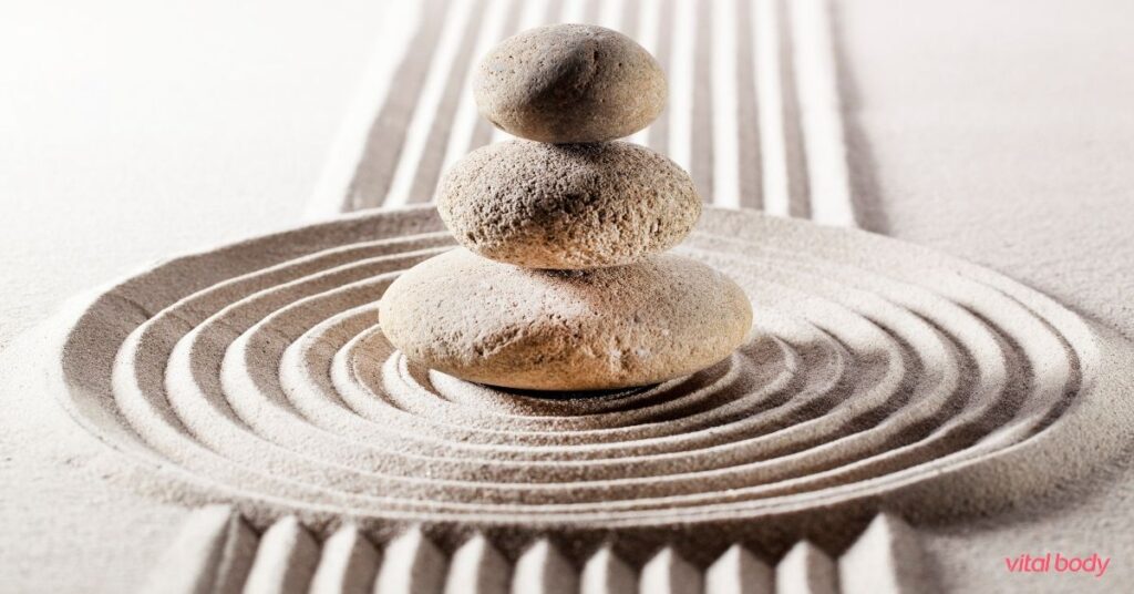 Stacked smooth stones on raked sand circles, a calm image for mindful eating and guided meditation