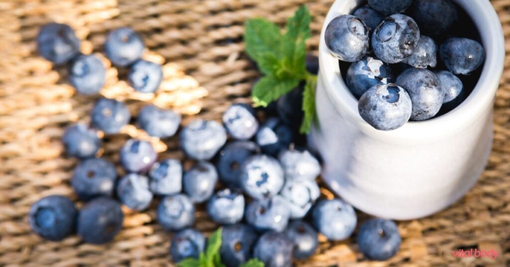 Fresh blueberries with mint spilling from a white cup, a simple whole food for real-life nutrition